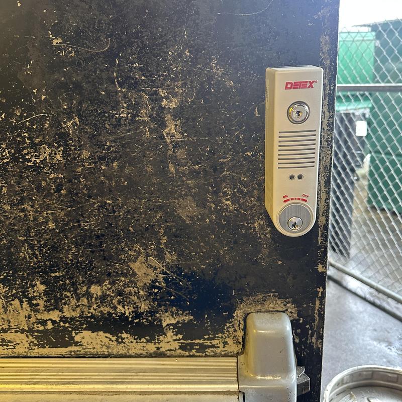 Detex alarm exit device on weathered metal door