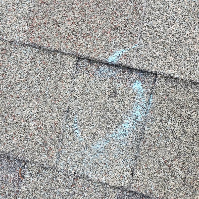 Roof shingles with hail damage marked in blue chalk