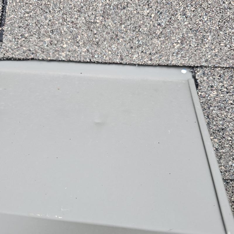 Metal roofing panel with hail dent near shingle edge