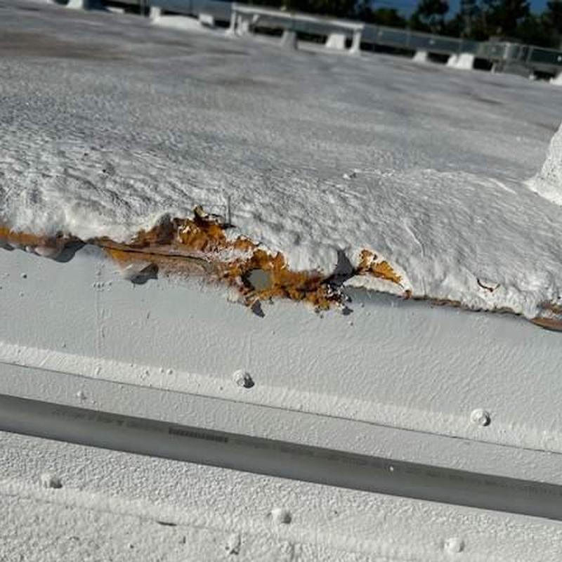 Spray foam roof damage with rust and coating failure