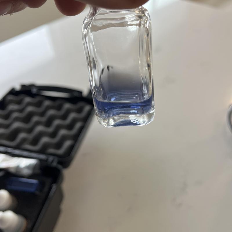 Water softener test vial with blue liquid inside