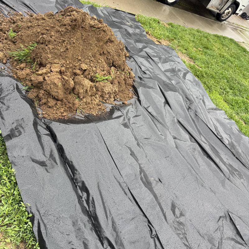 Main water service line excavation with black tarp covering