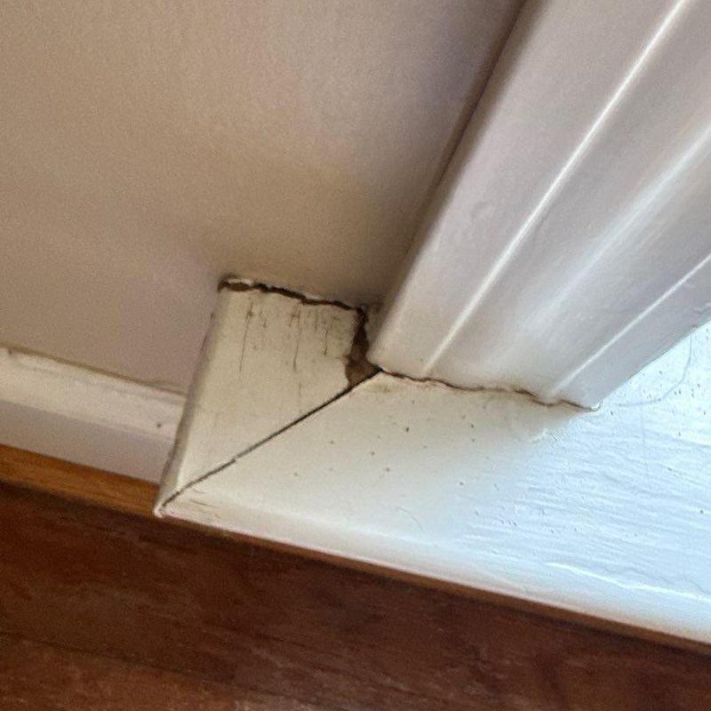 Doorframe wood trim corner with cracking and gaps