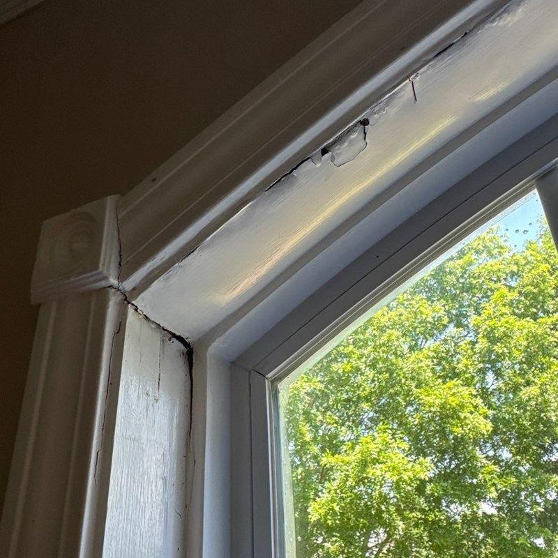 Window frame wood crack and paint damage near corner