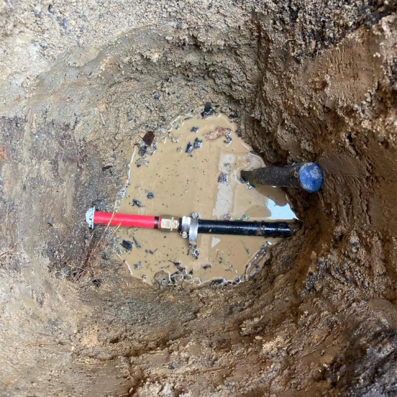 Main water line with repair clamp in muddy hole