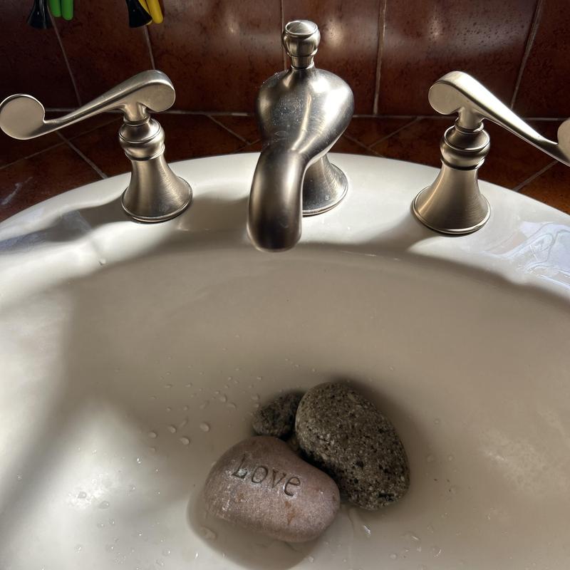 Bathroom sink faucet with decorative stones inside basin