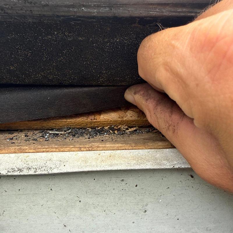 Roof flashing inspection showing damaged wood and underlayment