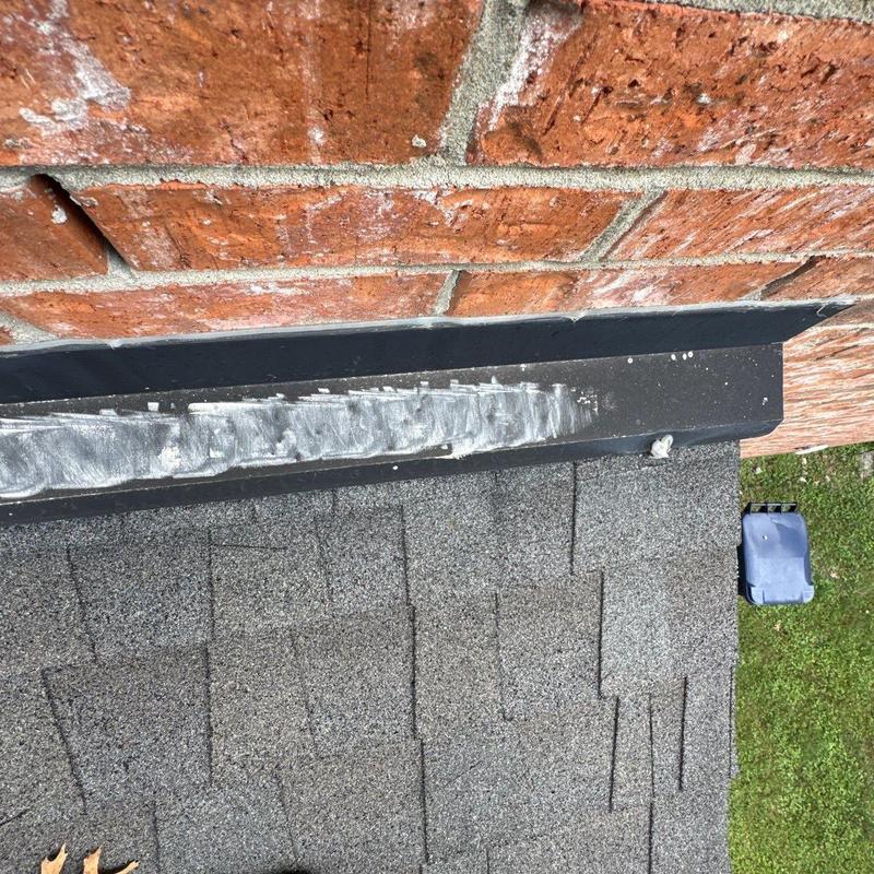 Roof flashing with sealant on brick wall and shingles