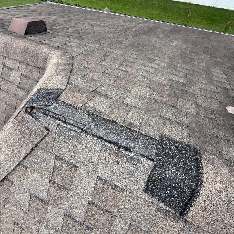 Asphalt shingle roof with hail damage on ridge vent
