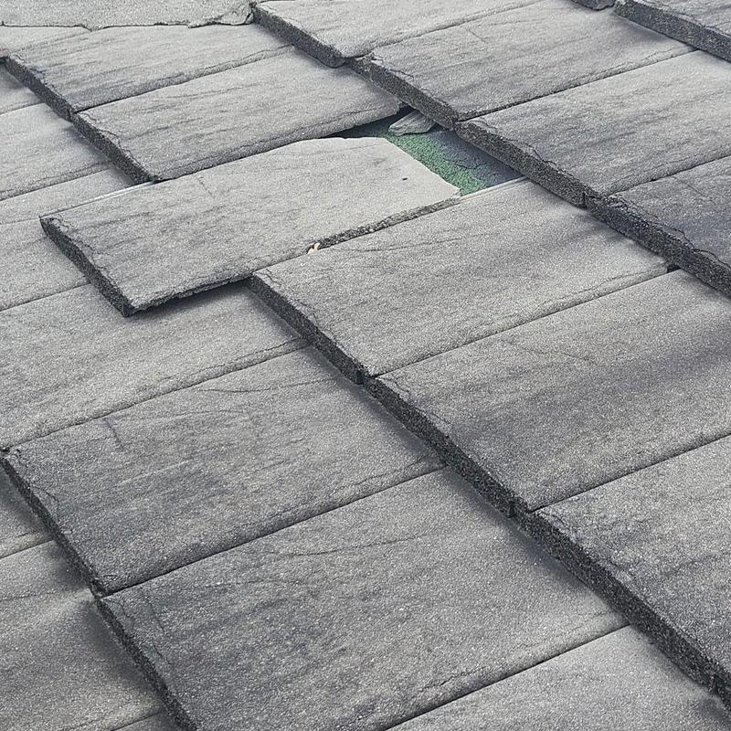Concrete tile roof with lifted damaged tile