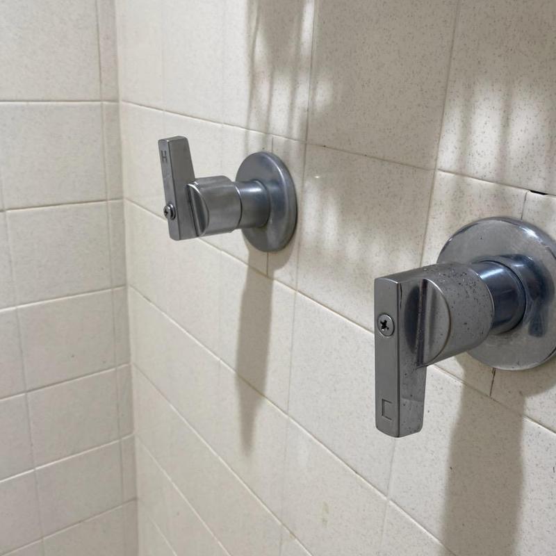 Two-handle shower faucet stems on tiled wall