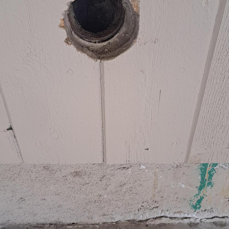 Kitchen drain pipe opening in wall with surrounding damage