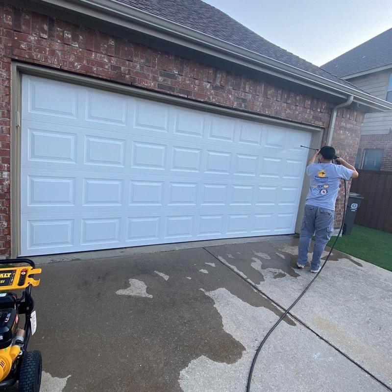 Garage door exterior painting with worker cleaning driveway