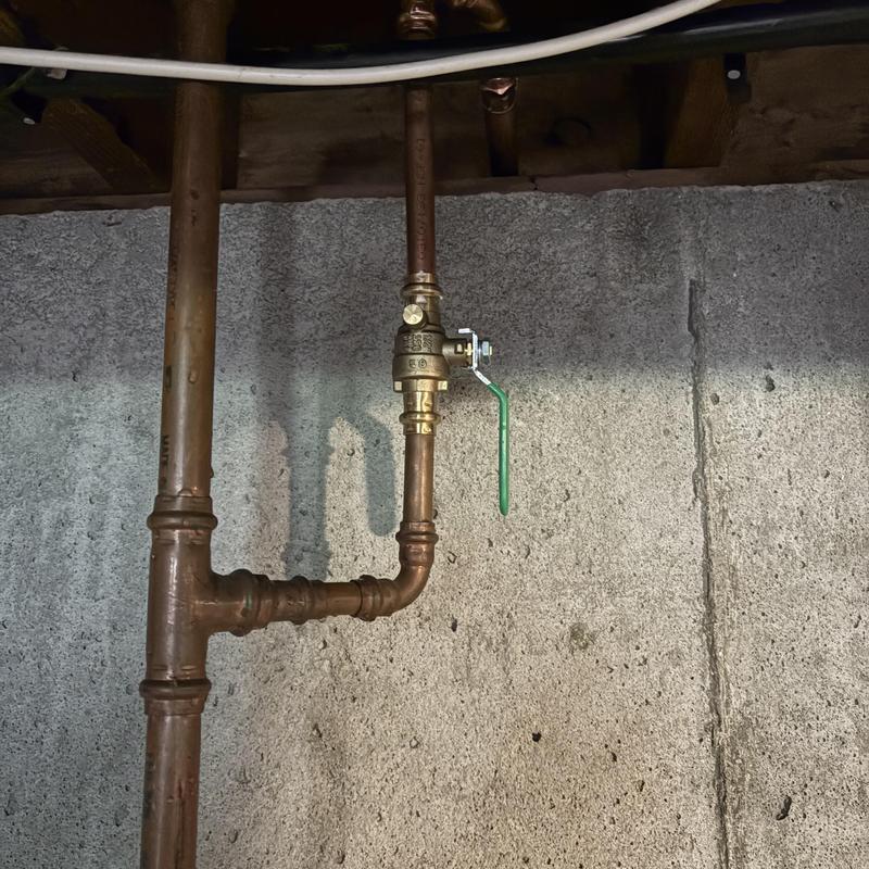 Copper water shutoff valve with green handle installed