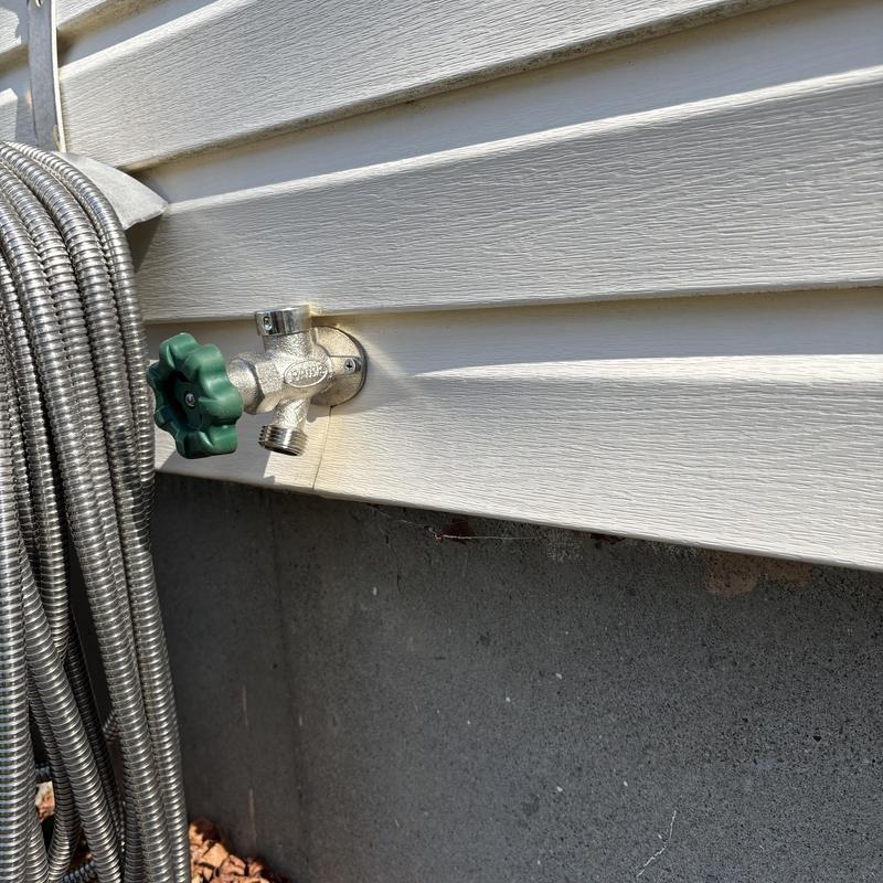 Outdoor frost-free sillcock with green handle and hose