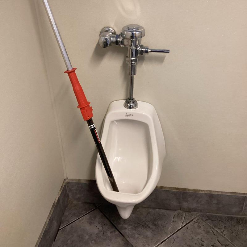 Urinal drain with plumbing snake clearing blockage