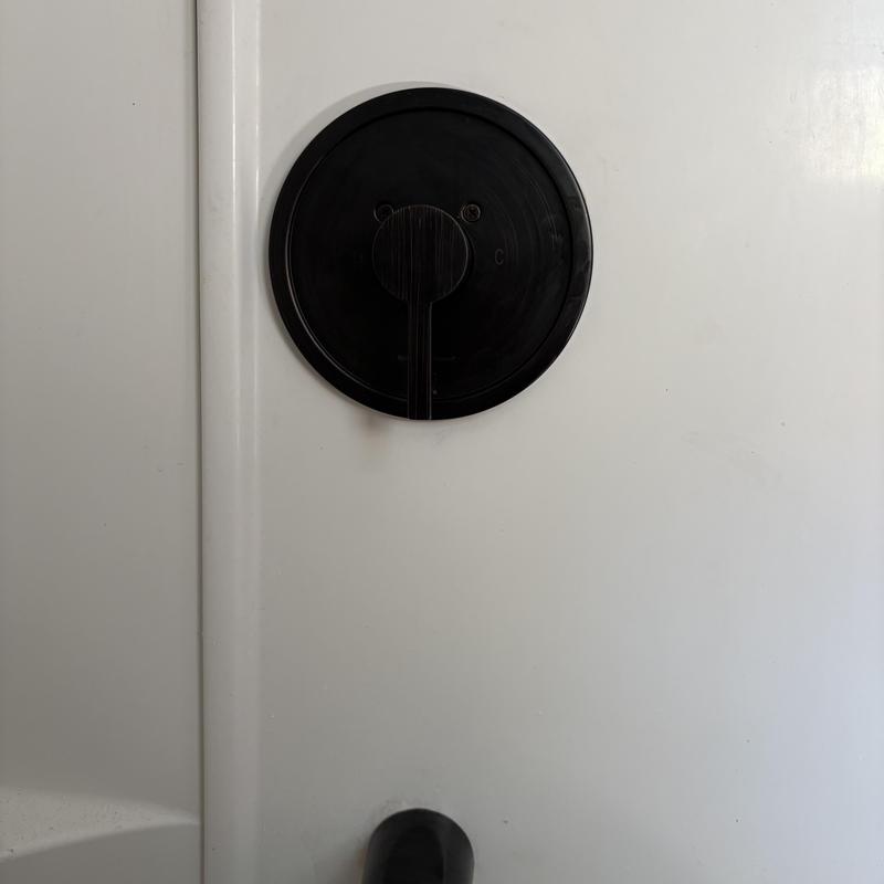 Shower valve trim package on white fiberglass wall