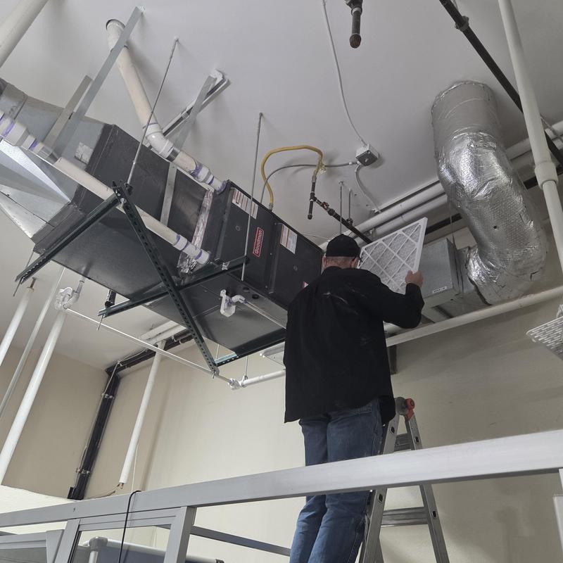 HVAC air handler unit filter replacement on ladder