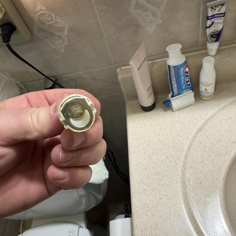 Faucet cartridge held near bathroom countertop items