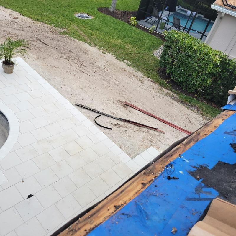 Tile roof eave with removed damaged decking and blue tarp