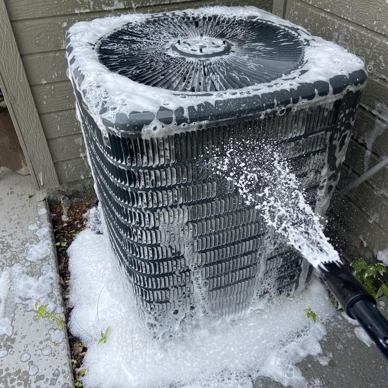 Outdoor air conditioner condenser being cleaned with foam