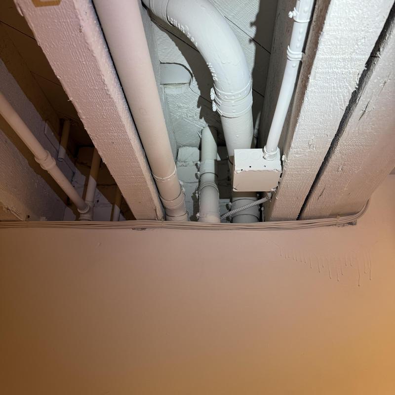 Bathroom ceiling plumbing pipes and electrical conduit under joists