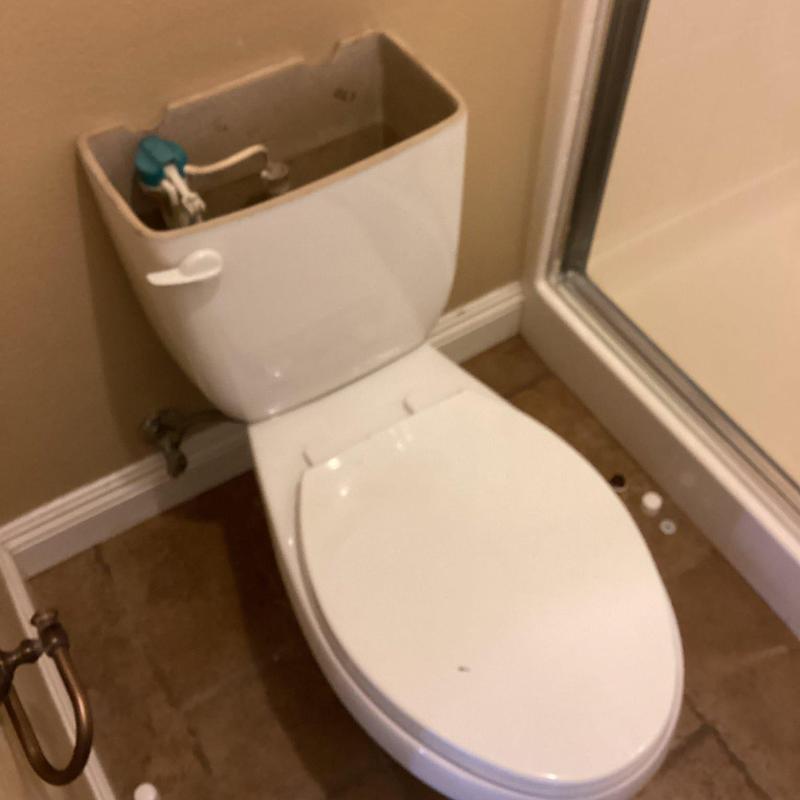 Toilet with open tank lid in bathroom next to shower