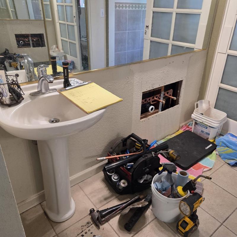 Bathroom vanity plumbing rough-in with tools on floor