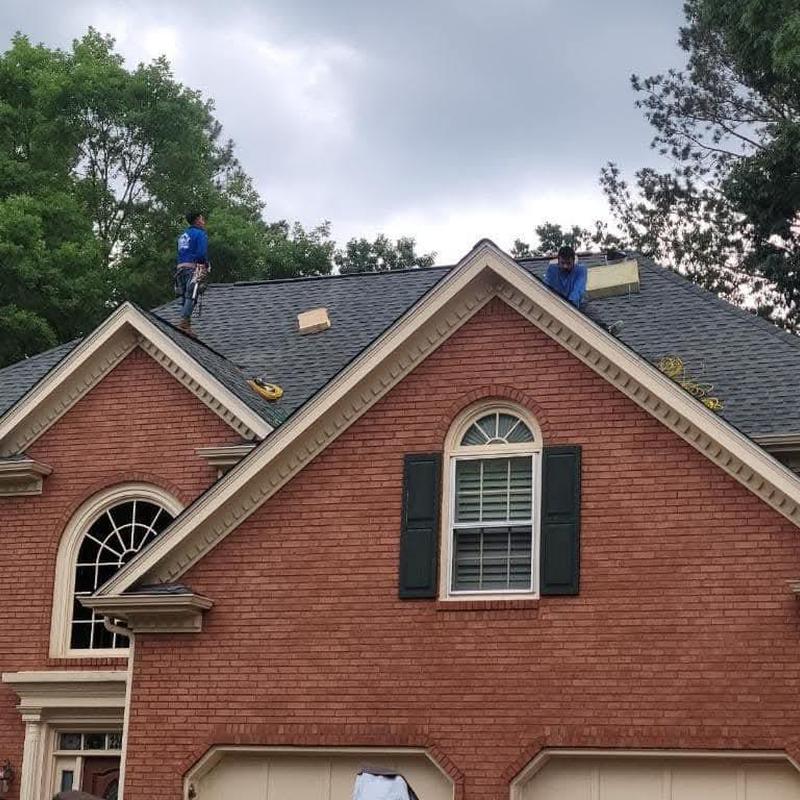 Asphalt shingle roof with workers installing in Hiram