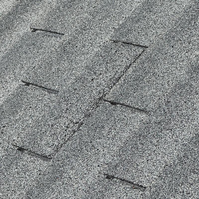 Asphalt shingle roof with lifted and damaged shingles