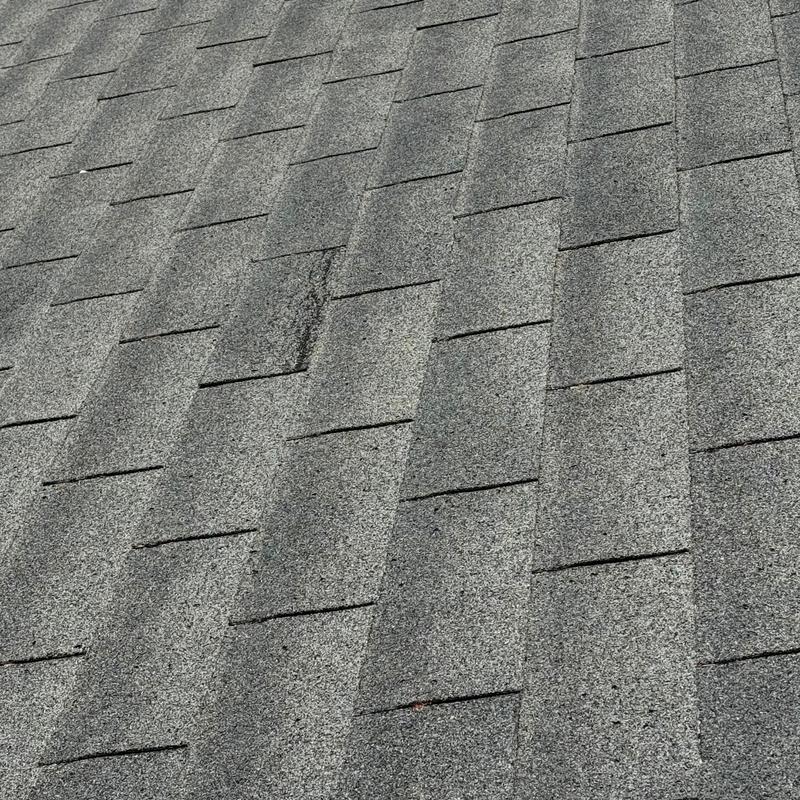 Gray asphalt shingles roof close-up with minor wear