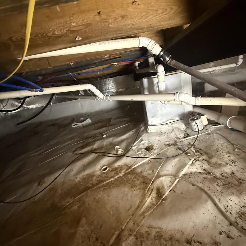 PVC drainage pipes in crawl space near furnace system