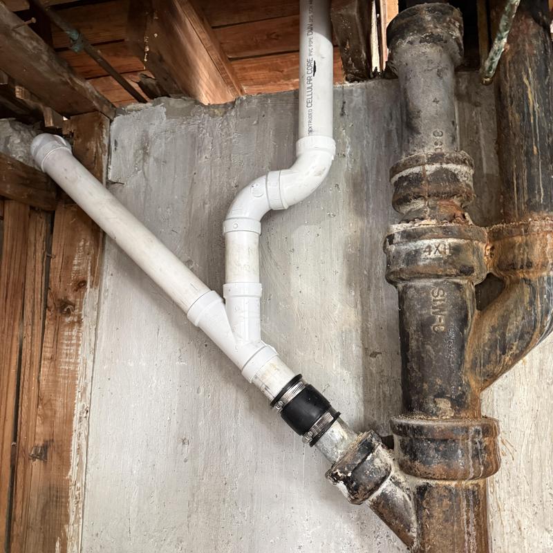 PVC and cast iron drain pipes with connectors in basement