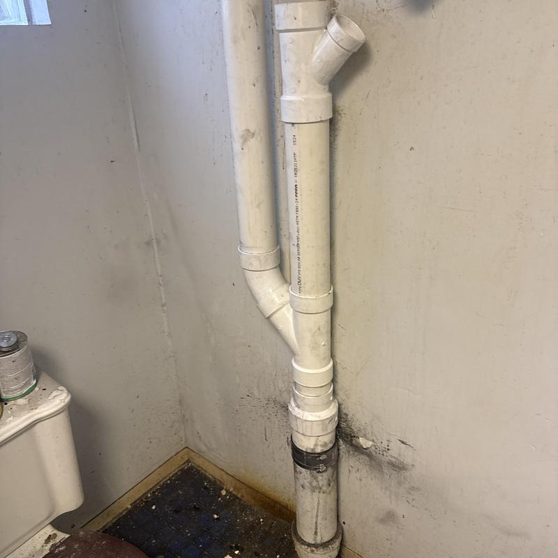 PVC plumbing stack with fittings in basement corner