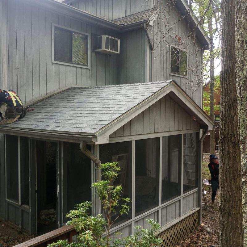 Asphalt shingle roof section with worker repairs Asphalt shingle roof section with worker repairs