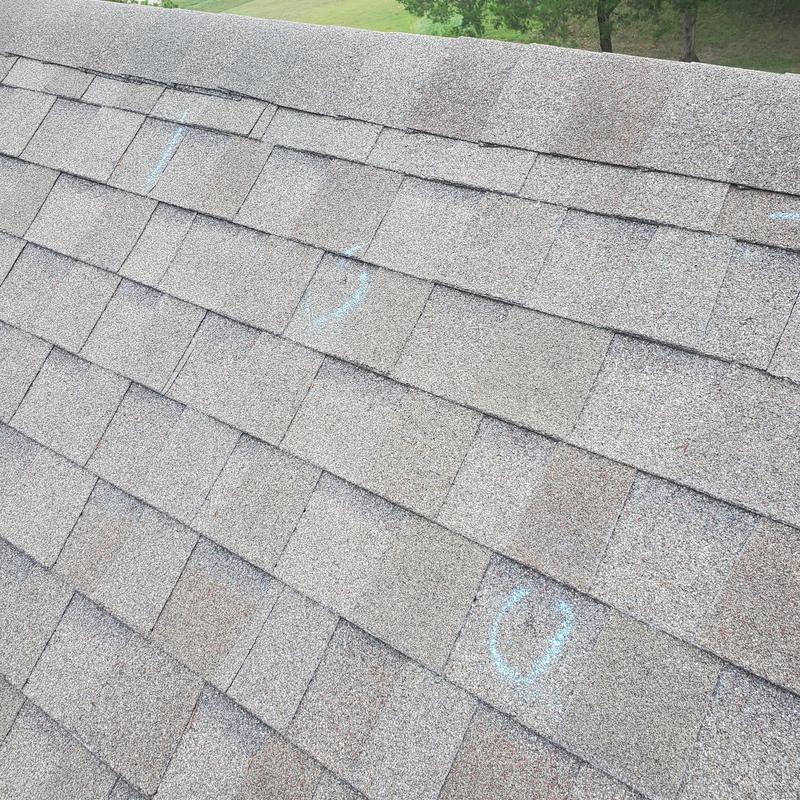 Asphalt shingles with hail damage markings on roof