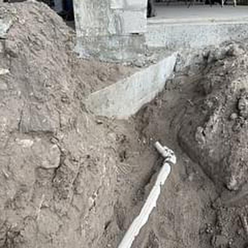 Rainwater leader pipe extension in backyard trench