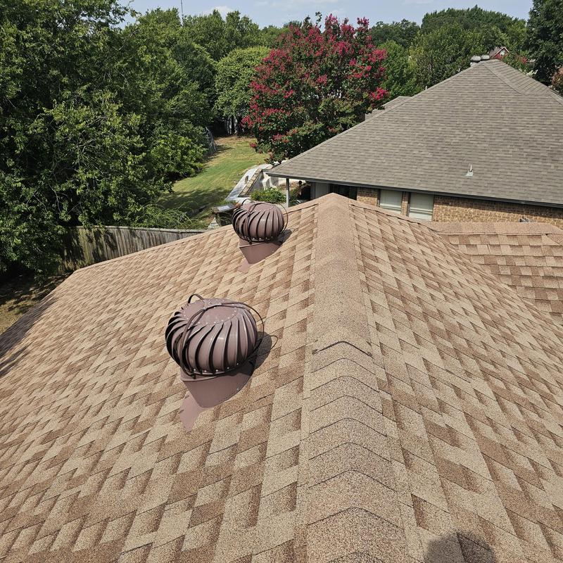 Asphalt shingle roof with turbine vents under clear sky