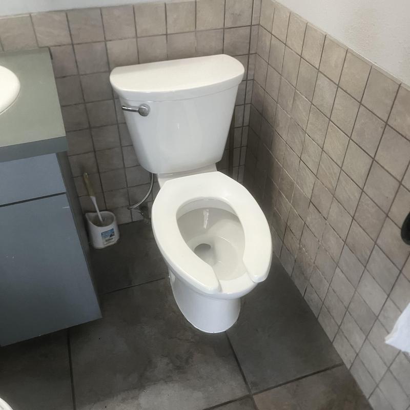 Commercial toilet installed in men's restroom with recessed flange
