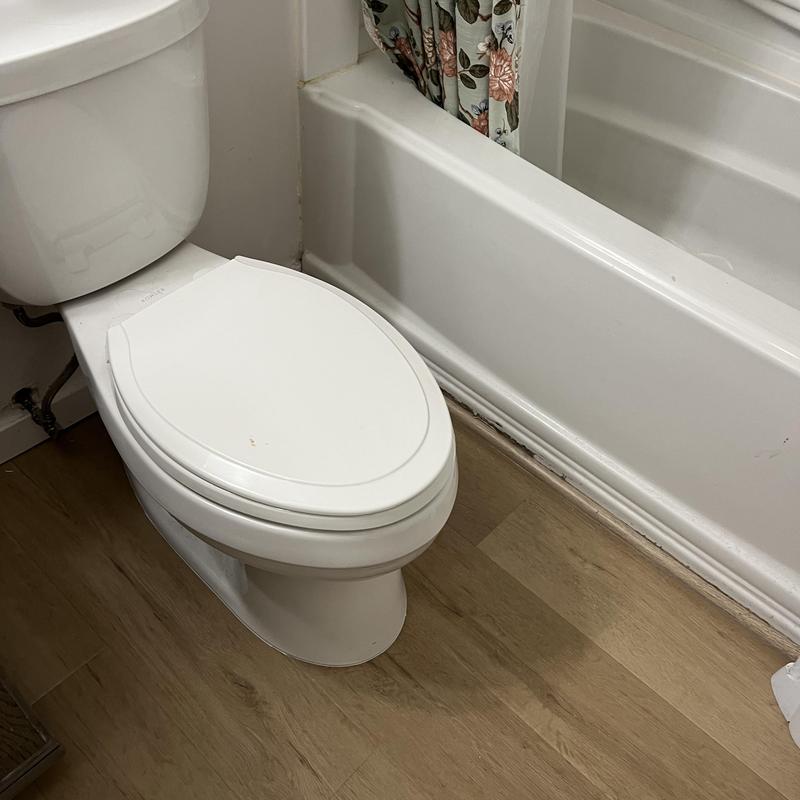 Toilet installation with new wax seal on wood floor