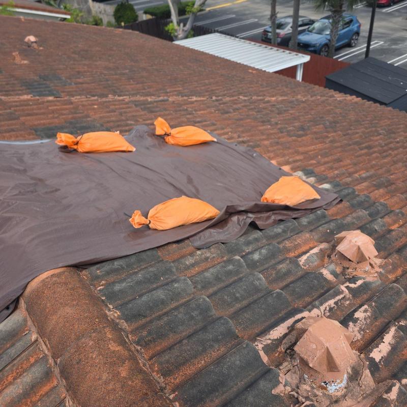 Tile roof with tarp and sandbags for protection Tile roof with tarp and sandbags for protection