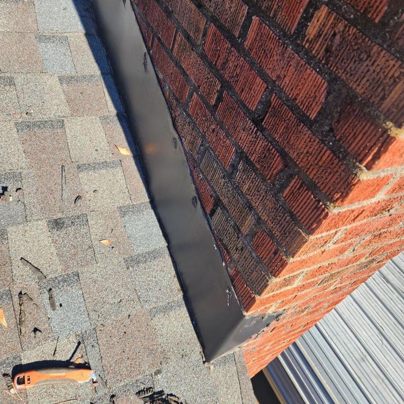 Chimney flashing on asphalt shingle roof corner Chimney flashing on asphalt shingle roof corner