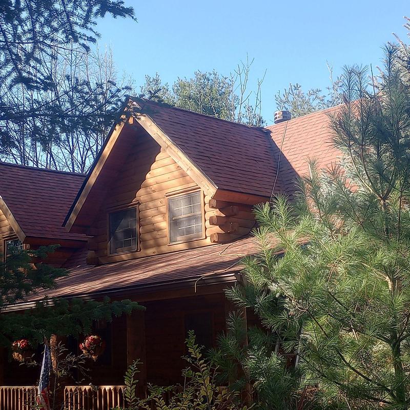 Asphalt shingle roof on log cabin surrounded by trees Asphalt shingle roof on log cabin surrounded by trees