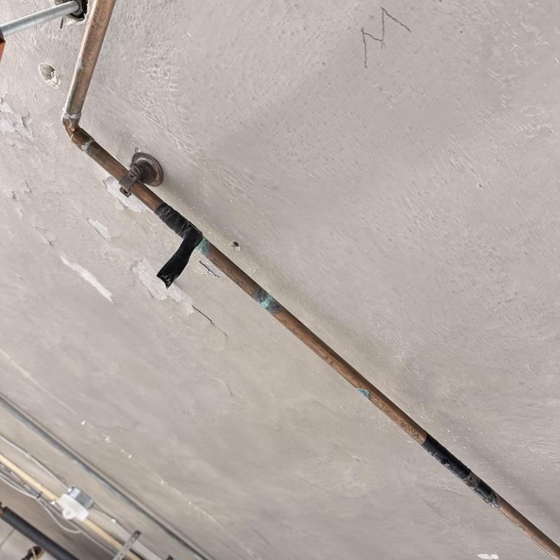 Copper piping with pinhole leaks taped on ceiling