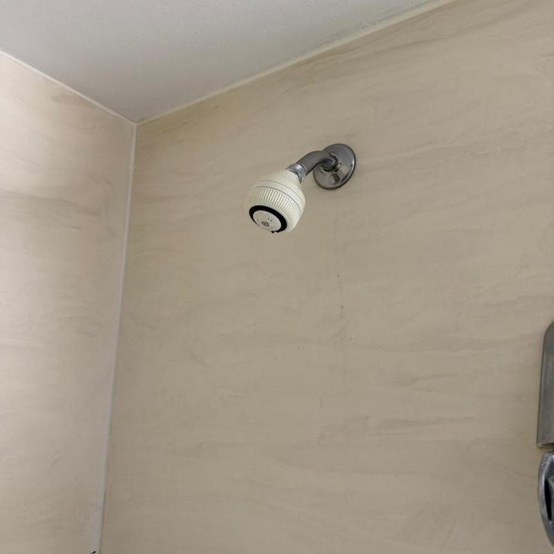 Shower head and pipe installation on beige wall