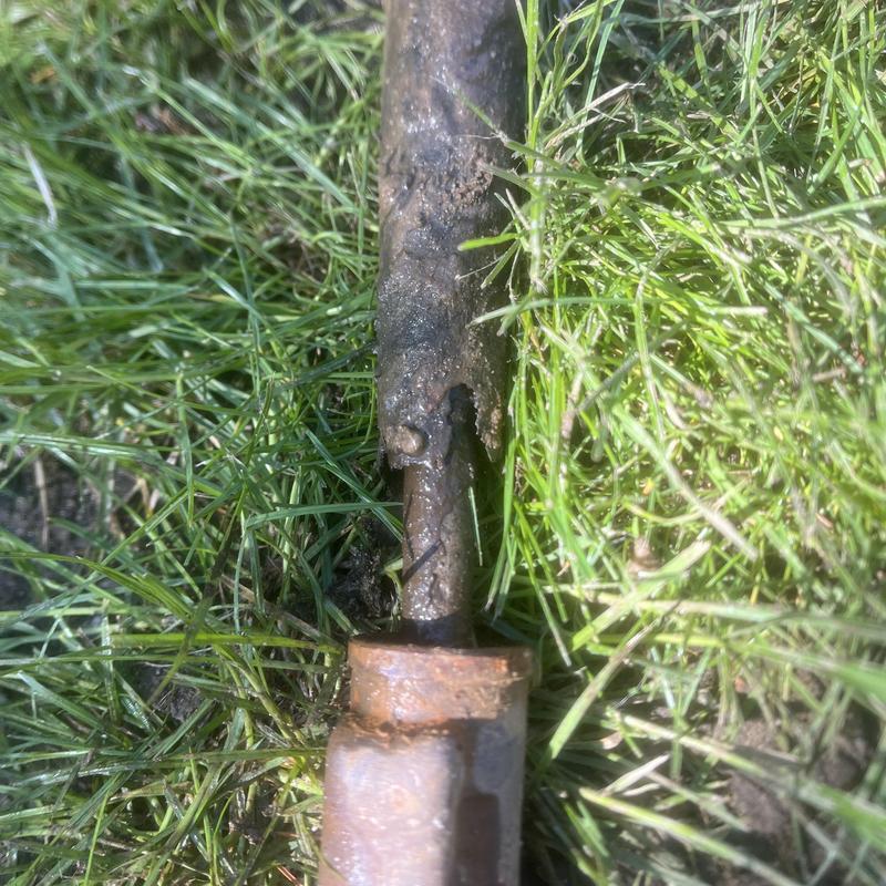 Outdoor hose bib pipe with rust damage in grass