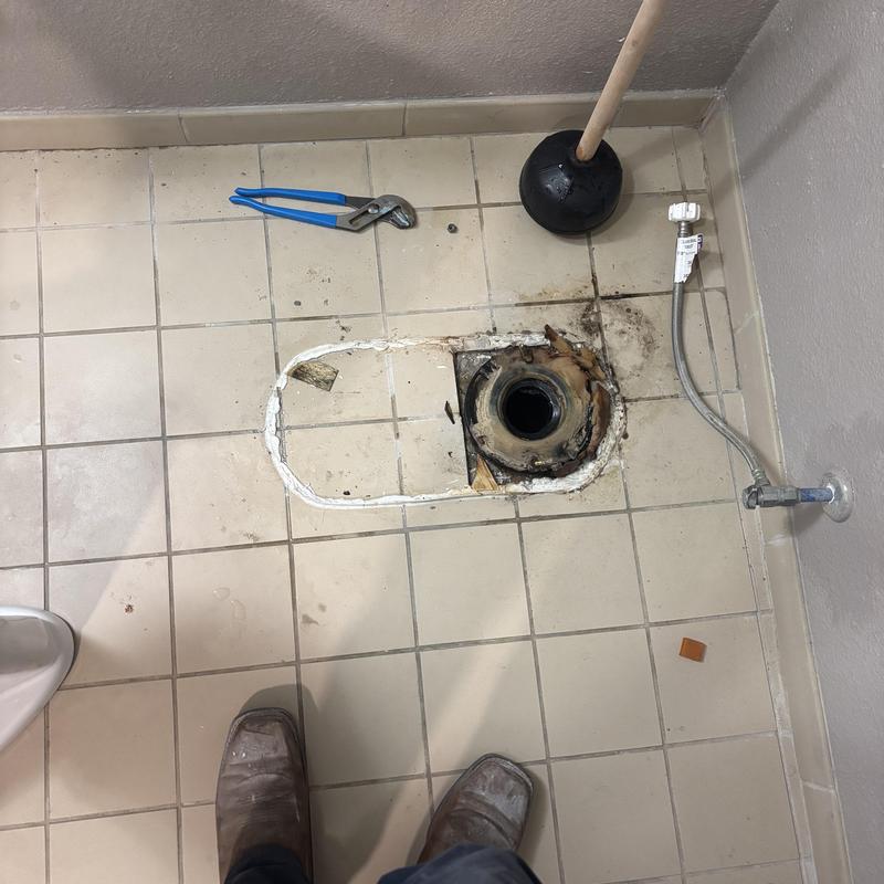 Toilet flange and water supply line on tiled floor