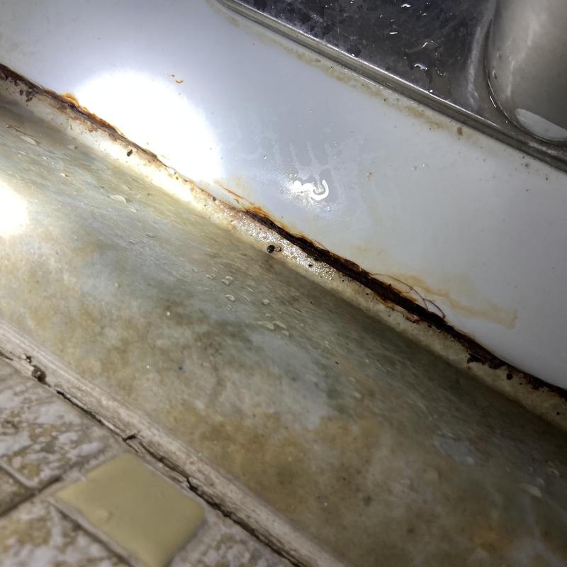 Cast-iron kitchen sink rust and water damage under rim