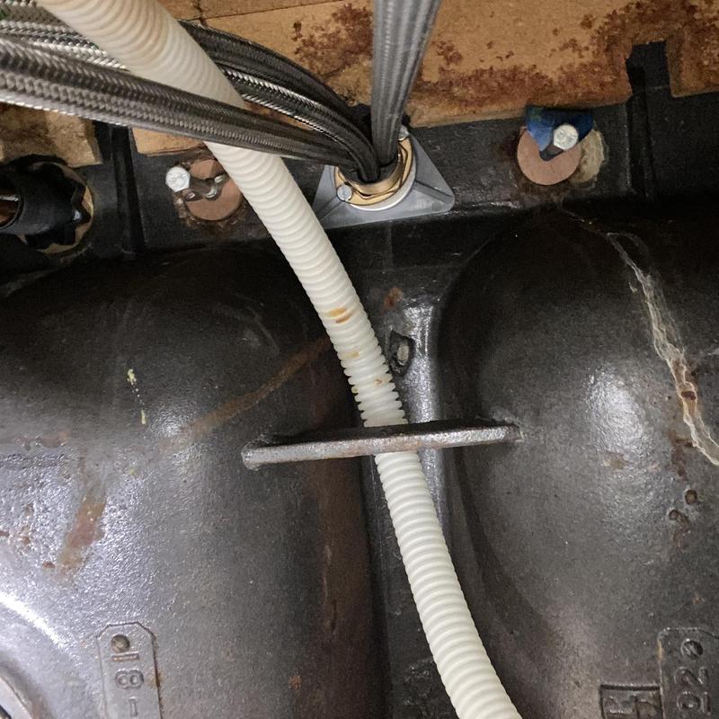 Cast-iron kitchen sink underside showing rust and pipes