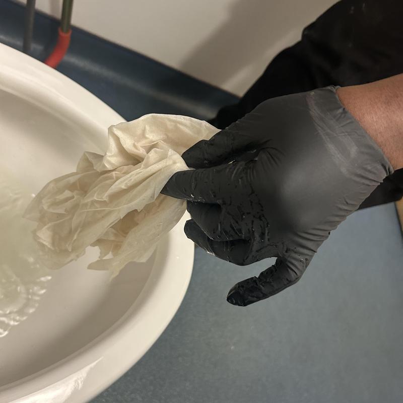 Toilet auger cleaning with gloved hand and paper towels Toilet auger cleaning with gloved hand and paper towels